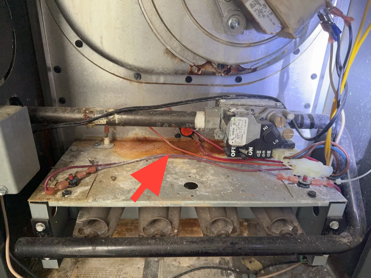 Rust staining on a furnace burner compartment from condensation draining back into the cabinet