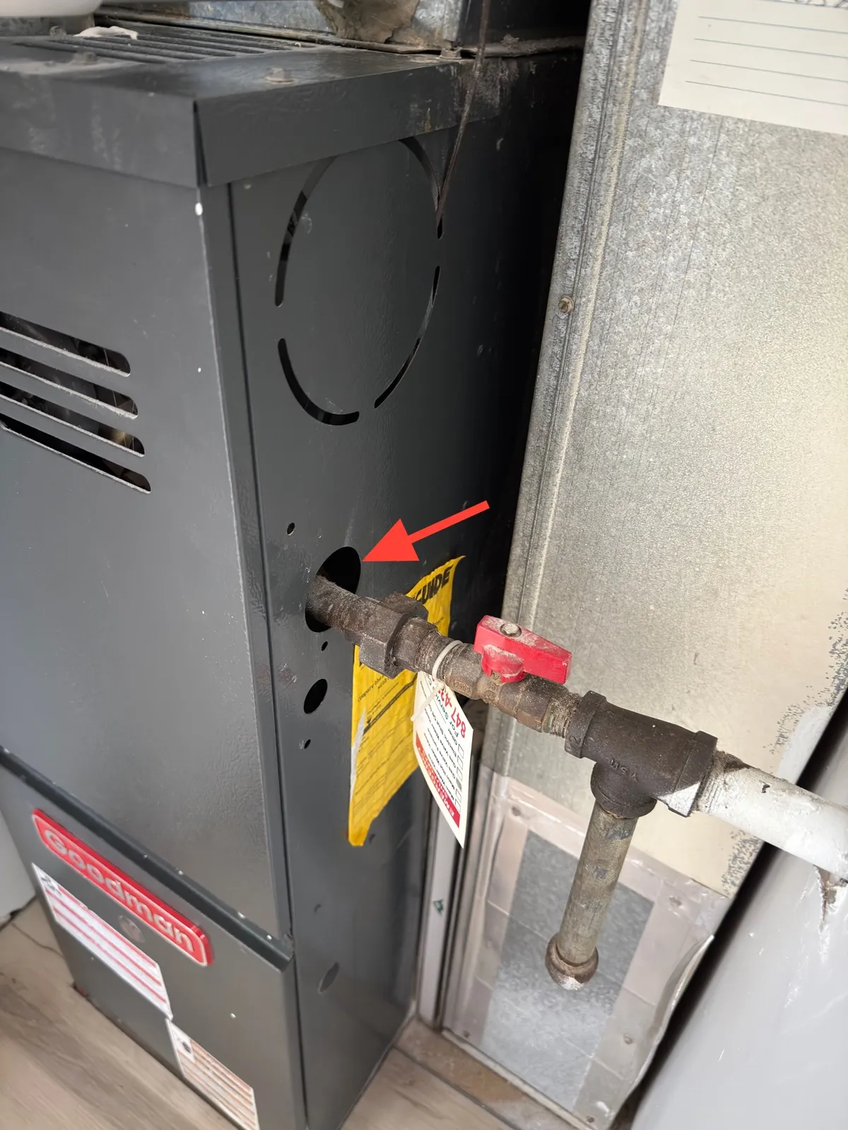 Gas pipe entering a furnace cabinet through a bare sheet-metal opening with no bushing