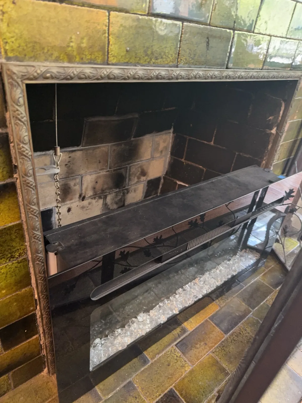 Tiled fireplace surround with an electric insert sitting in the old firebox