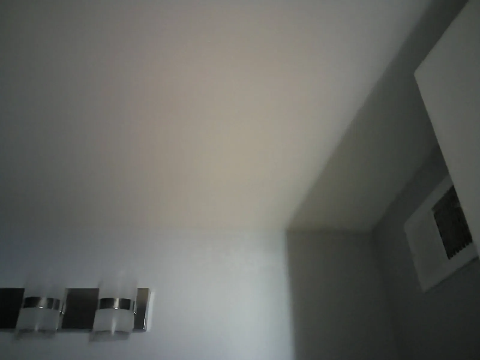 Plain photo of a white bathroom ceiling with an exhaust fan grille and vanity light, showing no stain